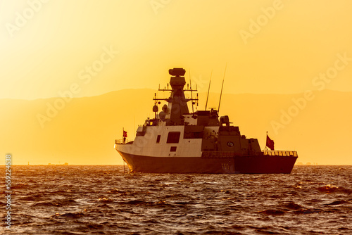 Turkish naval boat in the background of mountains and orange sunset sky