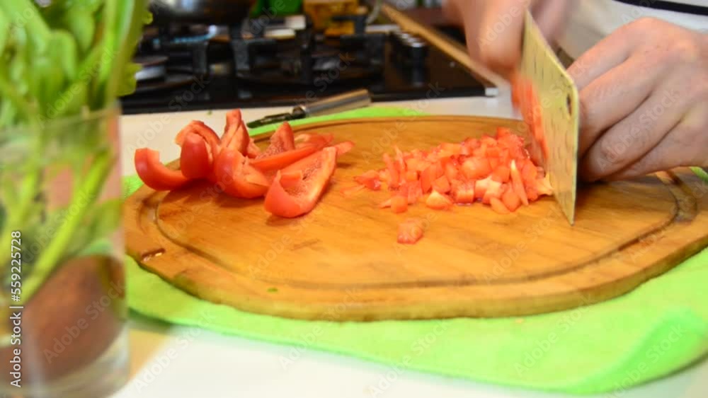 process of cutting red bell sweet peper with a kitchen cleaver on wooden chopping board. High quality FullHD footage