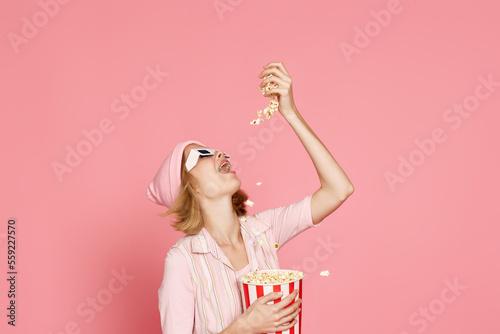 pleased blonde woman in t-shirt and hat eating popcorn
