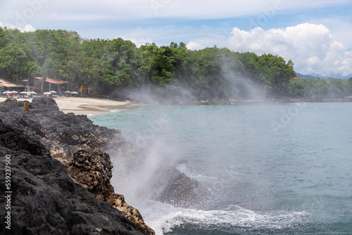 Beautiful nature fountain near Bias Tugel beach at the south of Bali island. White sand and rock shore.