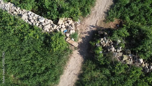 Garbage and plastic pollution in nature. High angle shot of green field with stone wall poluted with plastic bottles . High quality FullHD footage photo