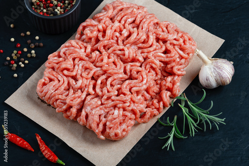 Fresh raw minced beef on backing paper and cutting board and ingredients