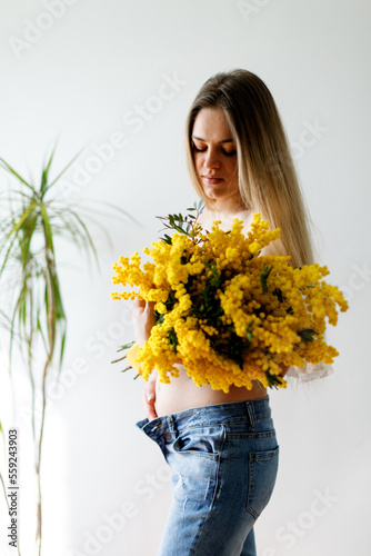 Third month of pregnancy. Beautiful pregnant woman with flowers. A series of photos of a pregnant girl. Concept of pregnancy, motherhood, mother's day.