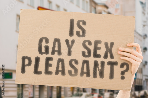 The question " Is gay sex pleasant? " is on a banner in men's hands with blurred background. Guy. Human. Person. Intercourse. Illegal. Love. Behavior. Sensual. Affection. Desire. Ass. Sexy. Gender