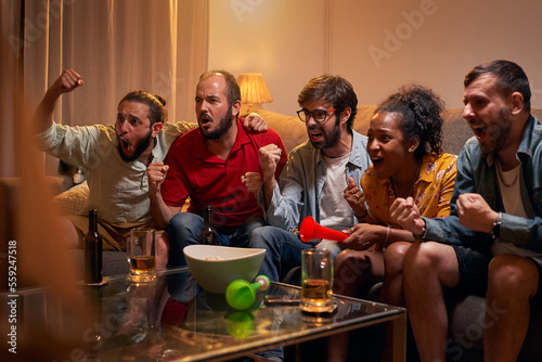 Caucasian joyful happy young friends woman and man at home hanging together cheering for favorite team and it winning match. People watching game on TV on sport channel, fun concept