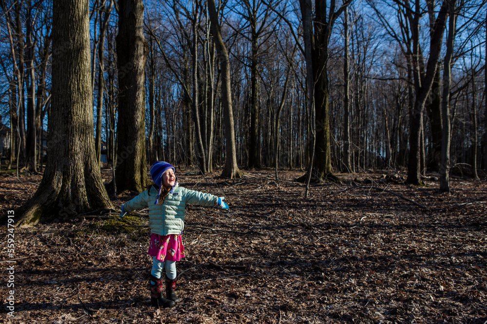 Happy girl with arms outstretched standing on field in forest Happy girl with arms outstretched standing on field in forest