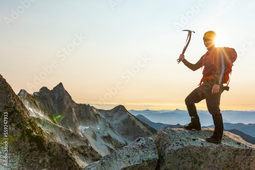 Portrait of male hiker with grappling hook standing on mountain against clear sky during sunset