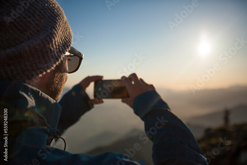 A man uses his phone to snap a photo of the view from the summit of Sauk Mountain. photo