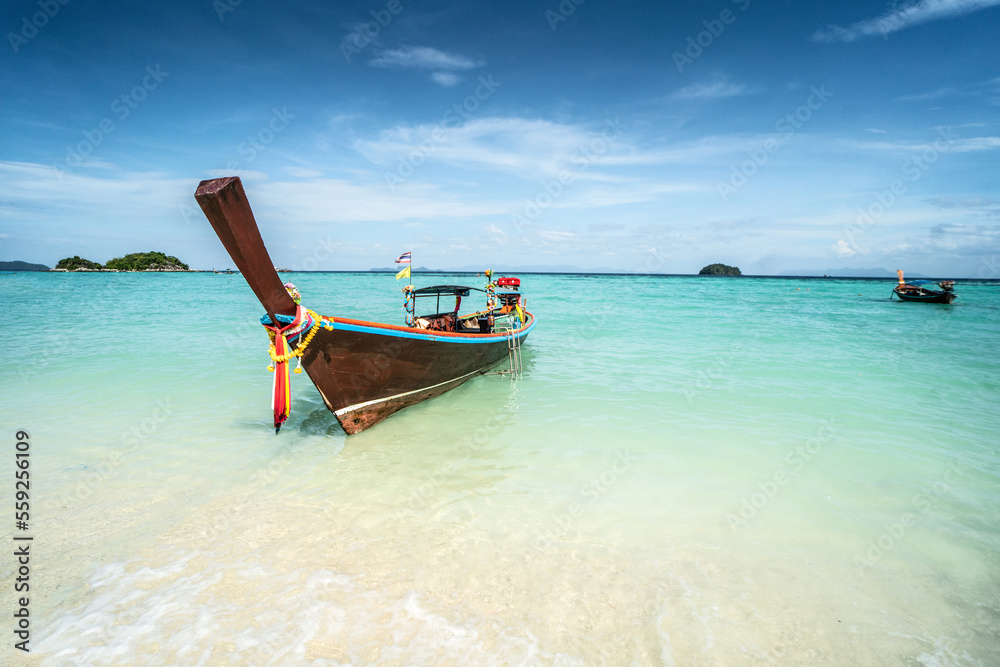 Long tail boat on tropical beach, Koh Lipe island, Thailand. Summer vacation, holiday concept. Blue sky. Long tail boat on tropical beach, Koh Lipe island, Thailand. Summer vacation, holiday concept. Blue sky.