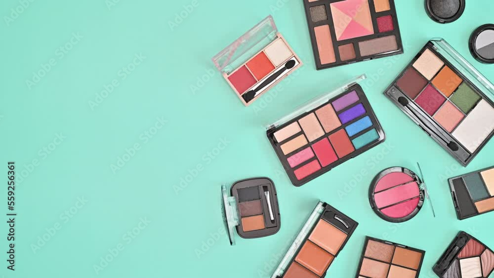 Make up Eye shadows appear on right side of pastel blue background. Flat lay. Stop motion