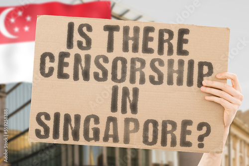 The question " Is there censorship in Singapore?" is on a banner in men's hands with blurred background. Media. Stamp. Censored. Control. Censor. Freedom. Information. Newspaper. Security. Censorship