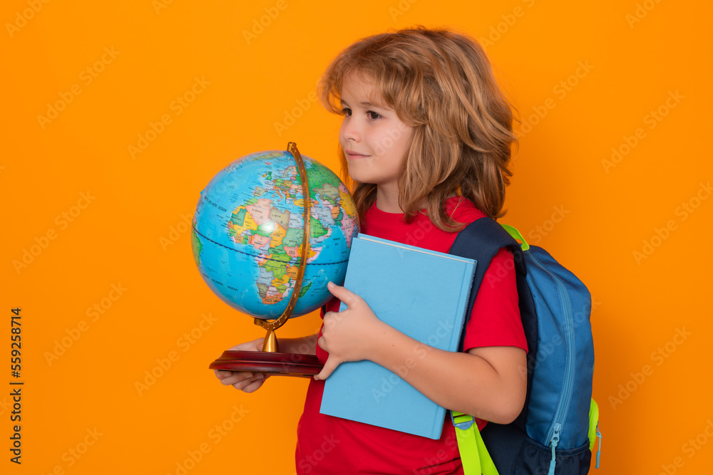 Fototapeta premium School kid hold world globe and book. Back to school. Funny little student boy from elementary school with book. Pupil on studio isolated background.