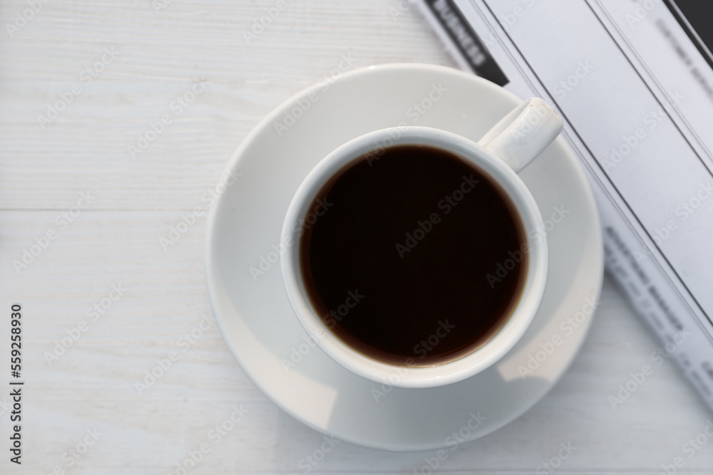 White cup with coffee and newspaper on wooden table in morning, flat lay White cup with coffee and newspaper on wooden table in morning, flat lay
