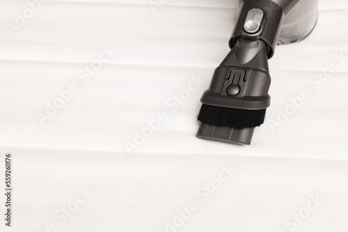 Fototapeta Naklejka Na Ścianę i Meble -  Modern vacuum cleaner on white mattress, closeup. Space for text