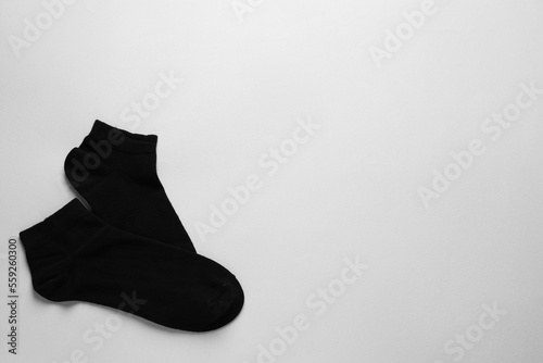 Pair of black socks on light grey background, flat lay. Space for text