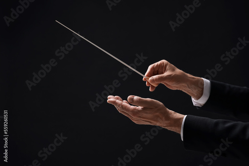 Professional conductor with baton on black background, closeup photo