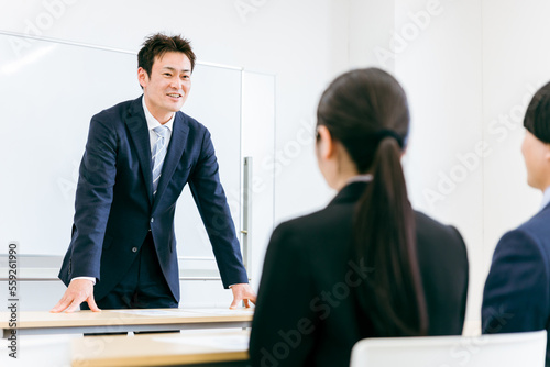 会議室で笑顔で話すスーツ姿の先生・講師・教師・ビジネスマンのアジア人男性 