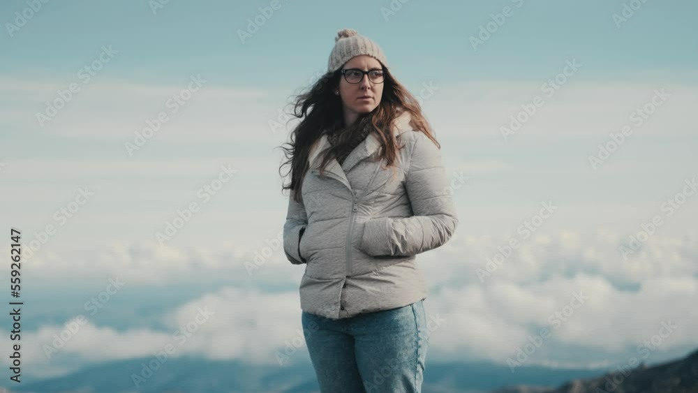 Medium shot of a young woman admiring the stunning landscape of mountains and clouds on the horizon while enjoying the beauty of nature in the mountains. Ideal for travel and adventure visuals. Medium shot of a young woman admiring the stunning landscape of mountains and clouds on the horizon while enjoying the beauty of nature in the mountains. Ideal for travel and adventure visuals.