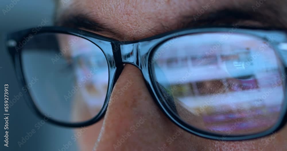Computer Screen Reflection On Glasses of male internet user searching information on websites at night. Closeup male eyes in glasses scroll internet websites, monitor screen reflect searching pictures