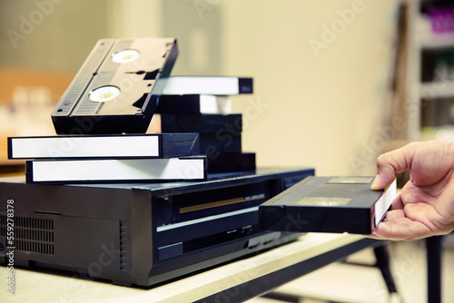 Foto Close-up hand chooses and put or insert video cassette tape VHS on video tape player concept of vintage electric retro style and electronic appliances multimedia player device old fashioned