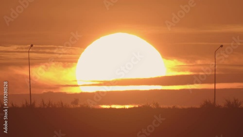 Daybreak in the morning is marked by the large sun rising gradually from above the horizon. In the winter morning, the sun rises amid a hazy or foggy sky. Dawn sunrise on the natural landscape.