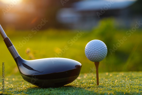 Golf clubs and golf balls on a green lawn in a beautiful golf course.