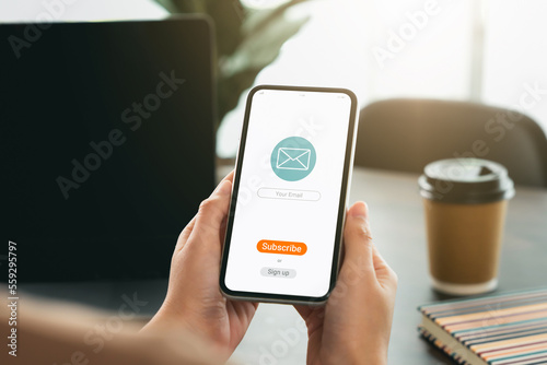 Hand holding smartphone and shows a digital screen of subscribe email notifications or sign up.