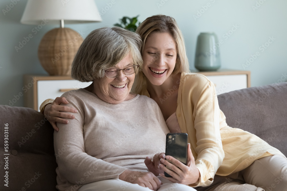 Cheerful elderly grandma woman and pretty young adult granddaughter girl talking on video call to family, using online app on smartphone for Internet communication, wireless connection Cheerful elderly grandma woman and pretty young adult granddaughter girl talking on video call to family, using online app on smartphone for Internet communication, wireless connection
