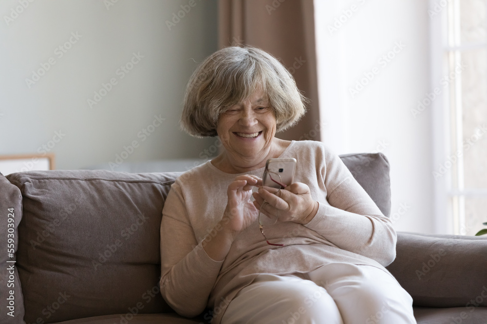 Happy positive old 80s grandma using smartphone at home, typing, making call, making online payment with virtual bank app, enjoying Internet communication, talking to family on cellphone