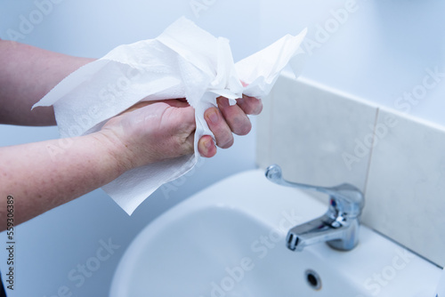 Handwashing - drying hands with paper towel after washing at basin