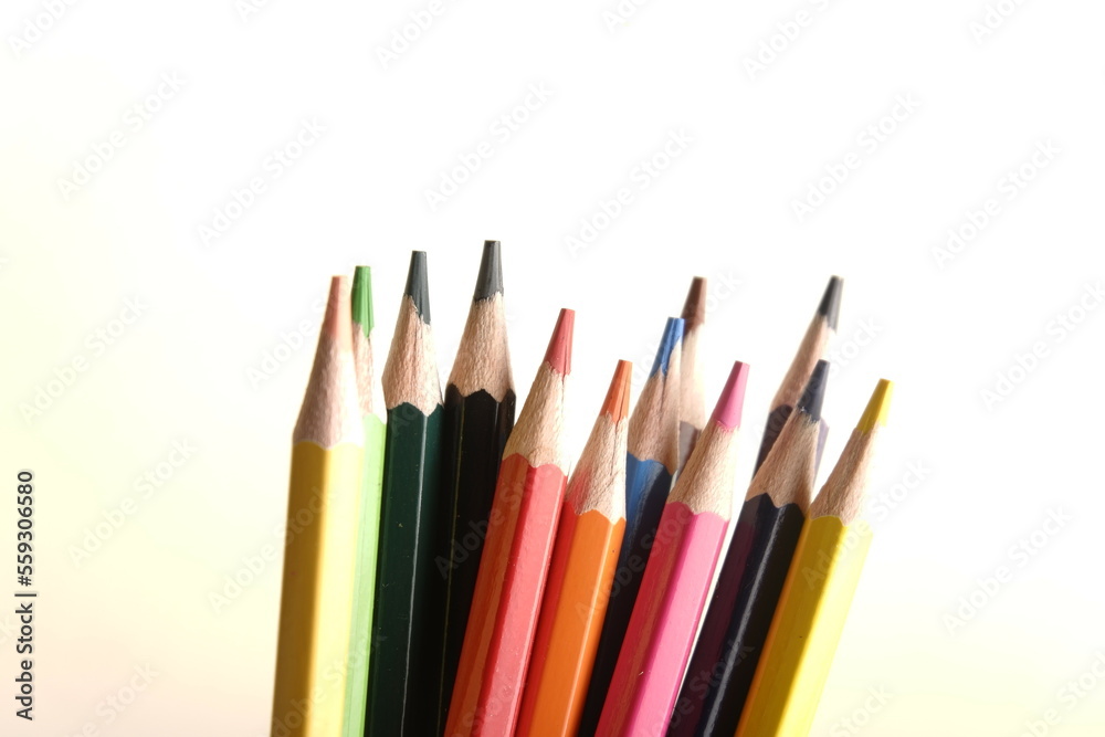 colored pencils against the background of a desk, notebook, white wall colored pencils against the background of a desk, notebook, white wall