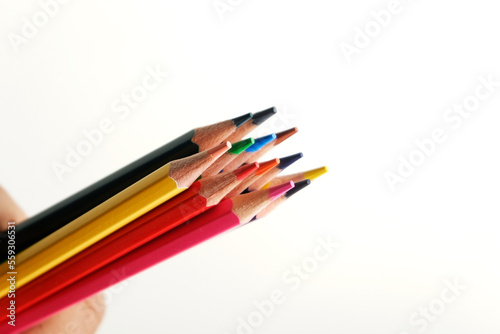 colored pencils against the background of a desk, notebook, white wall