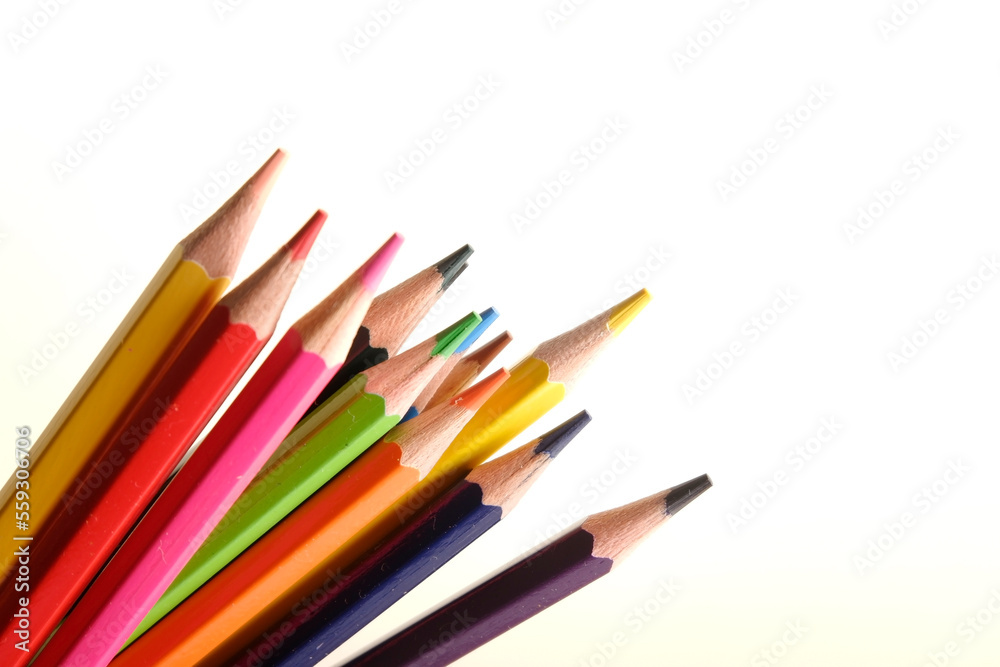 colored pencils against the background of a desk, notebook, white wall