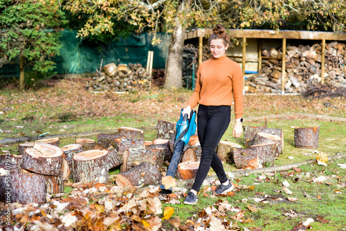 Young woman with her electric blower making piles of dead leaves to clean up the garden photo