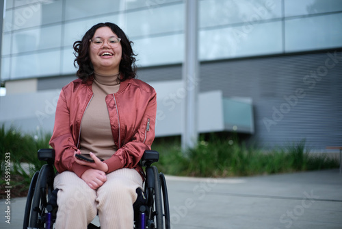 Smiling woman with a disability sitting in a wheelchair outside photo