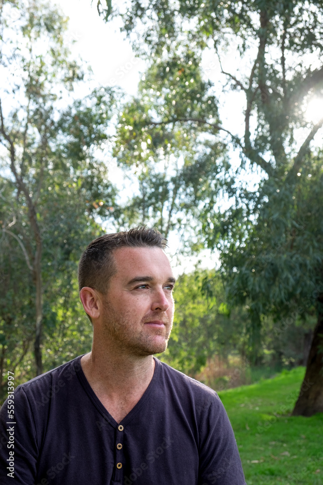 Caucasian male looking into the Distance surrounded by Trees Caucasian male looking into the Distance surrounded by Trees