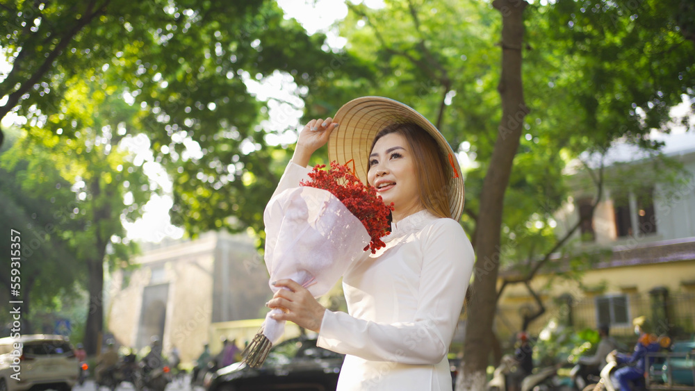 Fototapeta premium Portrait of Asian with bouquet flowers, Vietnamese woman girl traveling in Hanoi urban city town, Vietnam. People lifestyle.