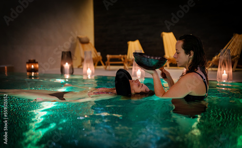 Therapeutic exercise in the pool. Woman receiving an aquatic therapy in the pool. Water relaxation. Music therapy and deep meditation.