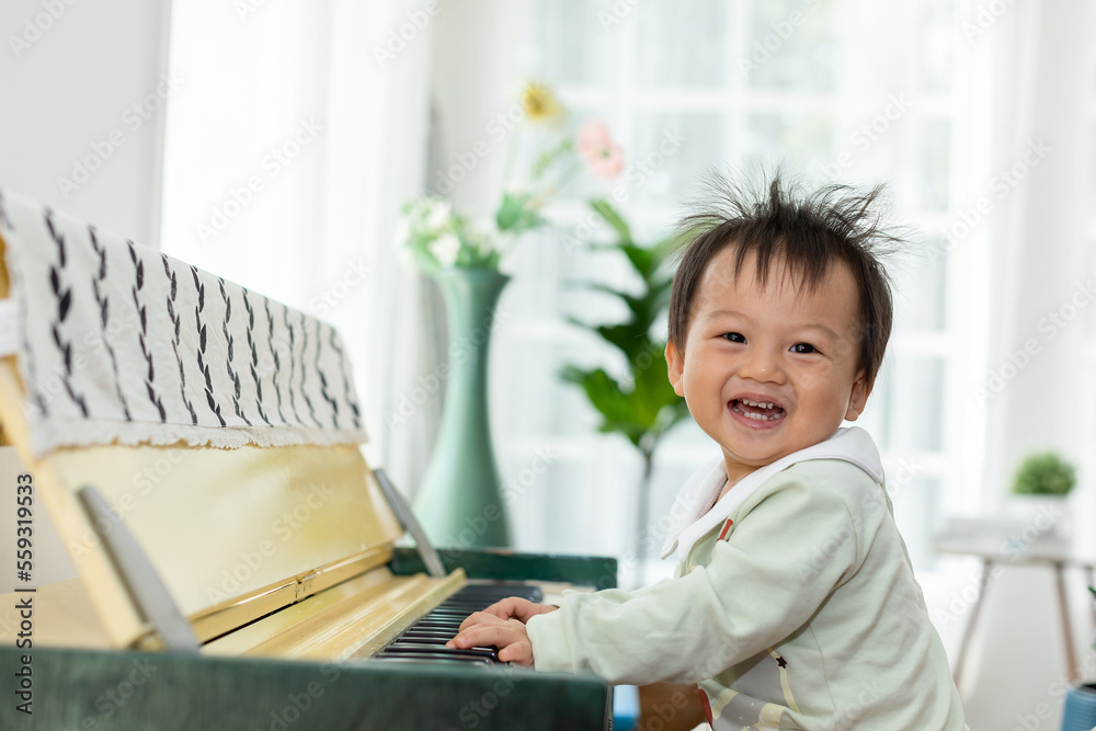 Happy Asian baby toddler smile playing and learning piano at home. Cheerful baby enjoy to develop skills with music. Positive activity to improved listening and hearing skill for little baby.good mood Happy Asian baby toddler smile playing and learning piano at home. Cheerful baby enjoy to develop skills with music. Positive activity to improved listening and hearing skill for little baby.good mood