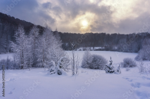 Evening after a heavy snowfall. Sunset over a frozen mountain lake. Everything is covered in snow