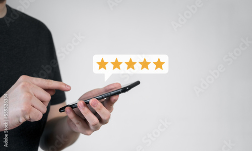Close up of customer using mobile phone with five stars best rating feedback icon. Customer service satisfaction evaluation concept.