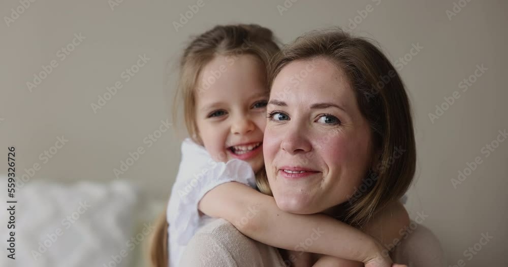 Close up portrait mom and little daughter. Preschooler girl piggyback loving laughing mother, spend carefree time on weekend together at home, feel unconditional love, enjoy playtime. Happy motherhood Close up portrait mom and little daughter. Preschooler girl piggyback loving laughing mother, spend carefree time on weekend together at home, feel unconditional love, enjoy playtime. Happy motherhood