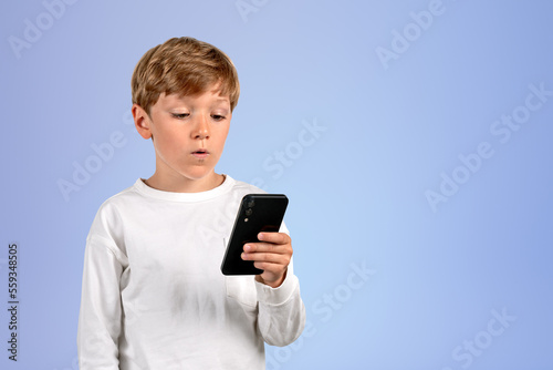 Pensive kid using smartphone on empty copy space background