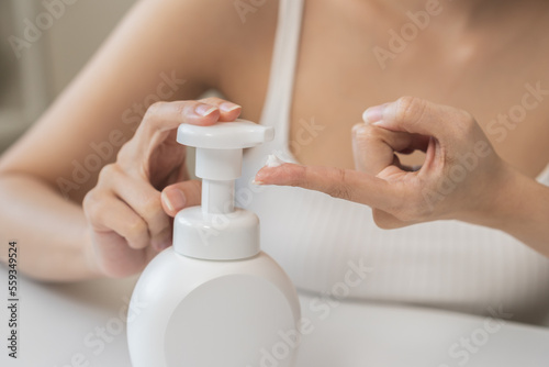 Healthy skin care,beauty asian young woman with lotion after shower bath at home, squeeze out moisturizer from bottle, putting on her hand. Skin body cream moisturizing lotion, routine in the morning.