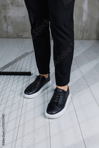 Modern men's shoes. Male legs in black pants and black casual sneakers. Men's fashionable shoes