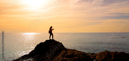 silhouettte of woman photographer taking photo on sunset at the sea photo