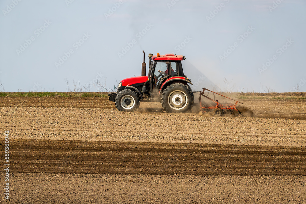 Fototapeta premium Springtime seeding preparations, tractor at work on the fertile fields