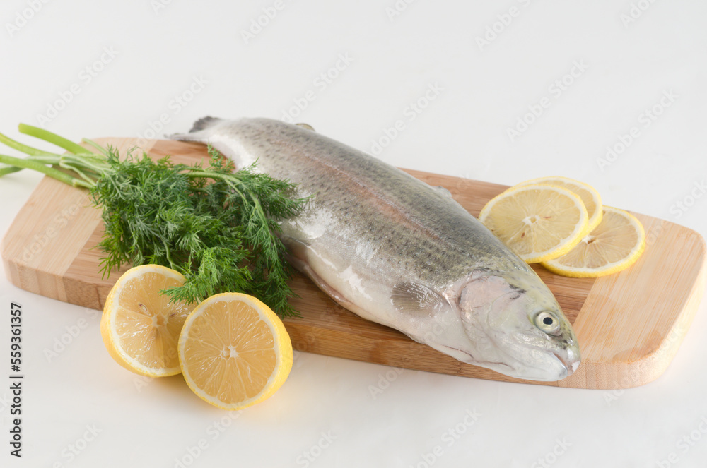 Raw trout on a wooden cutting board with sliced lemon and fresh dill Raw trout on a wooden cutting board with sliced lemon and fresh dill