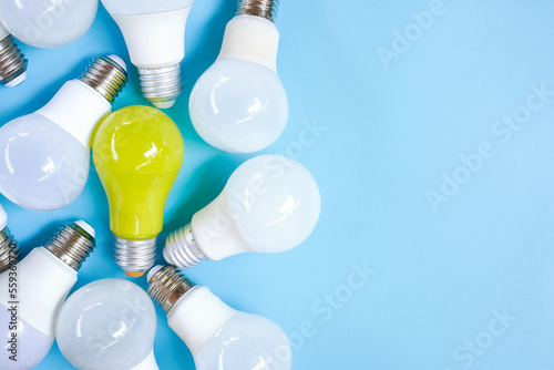 Quadro em tela Top view of pile of white and yellow light bulb on light blue background , uniqu