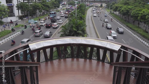 Jakarta, Indonesia - December 24, 2022 : Workers walking on the JPO (Pedestrian Bridge Pinisi) during work hours photo